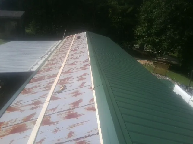 Old rusted panels beside newly installed green metal roofing — Wind Damage Roof Repair by Roofing Brothers in Stanford