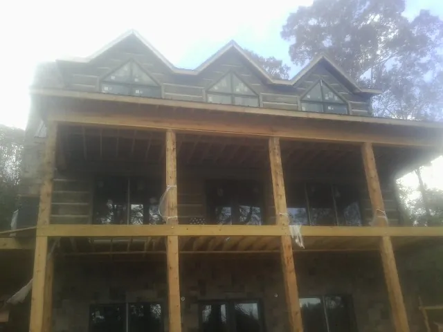 Dormers and porch framing on a large log home under construction — Roof Coating work by our crew in Stanford